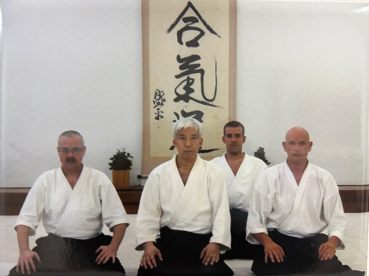 El sensei Pedro Fernández junto a un maestro japonés y otros alumnos, con la caligrafía "Aiki" al fondo