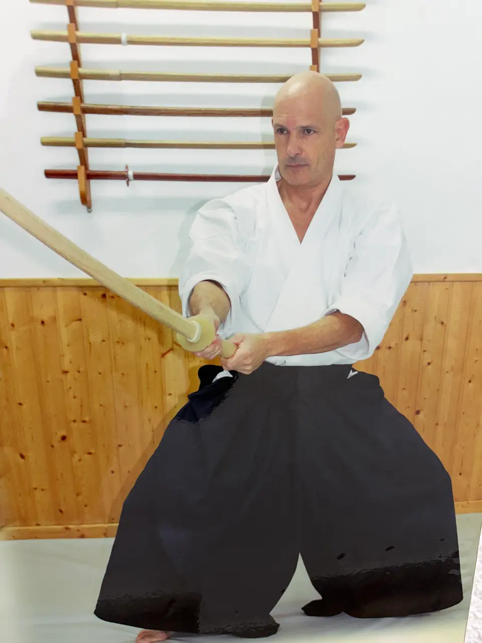 El sensei practicando Aikido con bokken frente al armero de armas